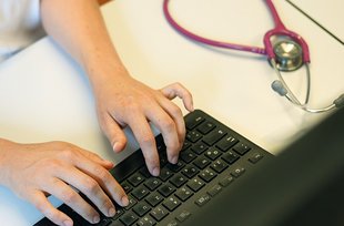 Ärztin tippt auf der Tastatur